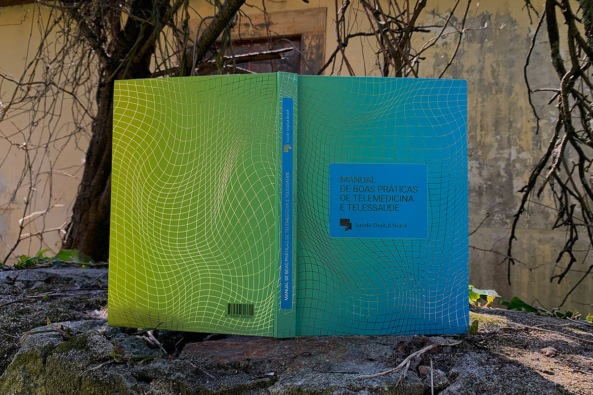 Guia de Medicina Digital da SDB, com capa em gradiente verde e azul, fotografado ao ar livre