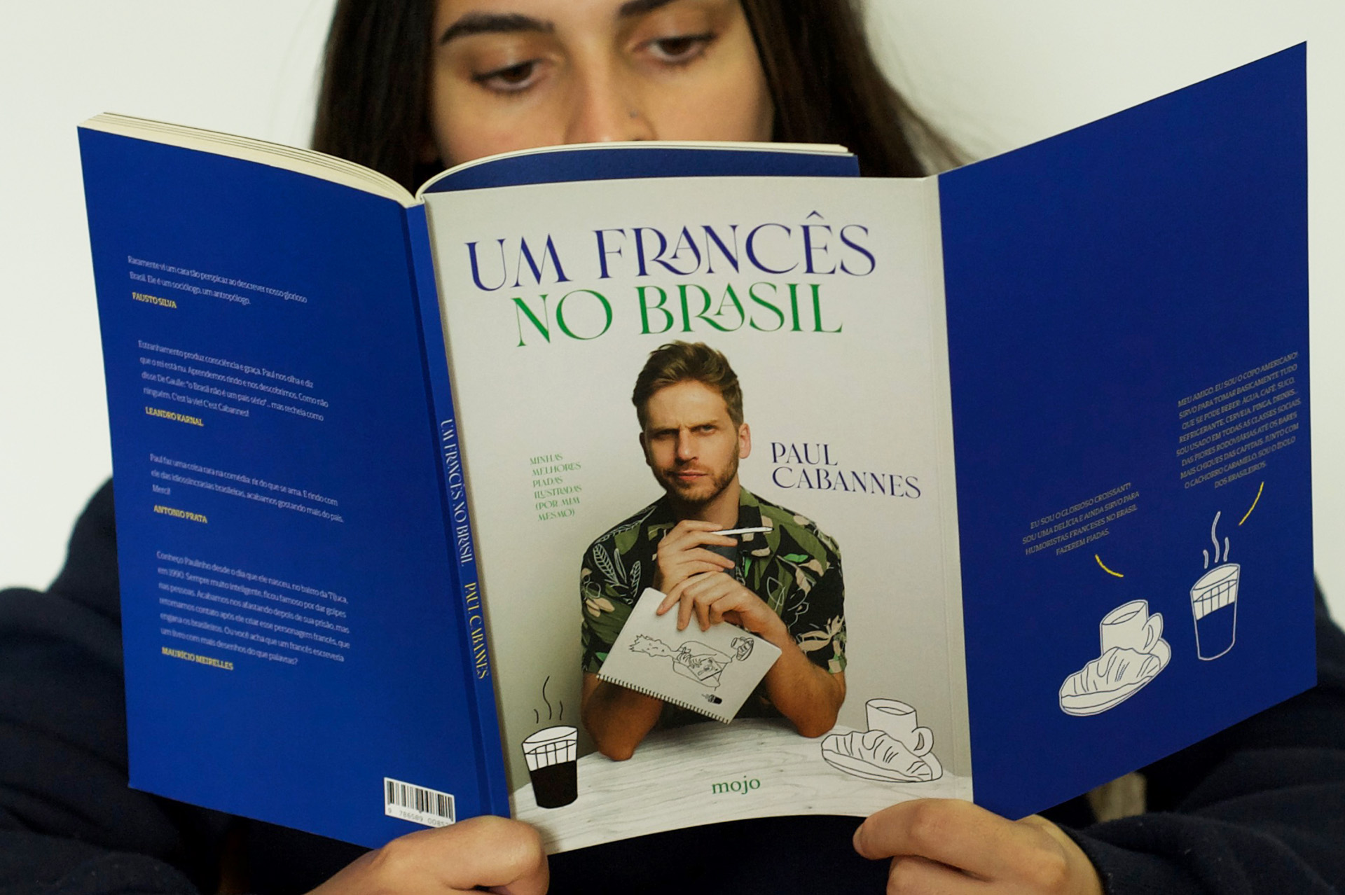 Pessoa a ler Um francês no Brasil, com a capa, a lombada e a contracapa à vista