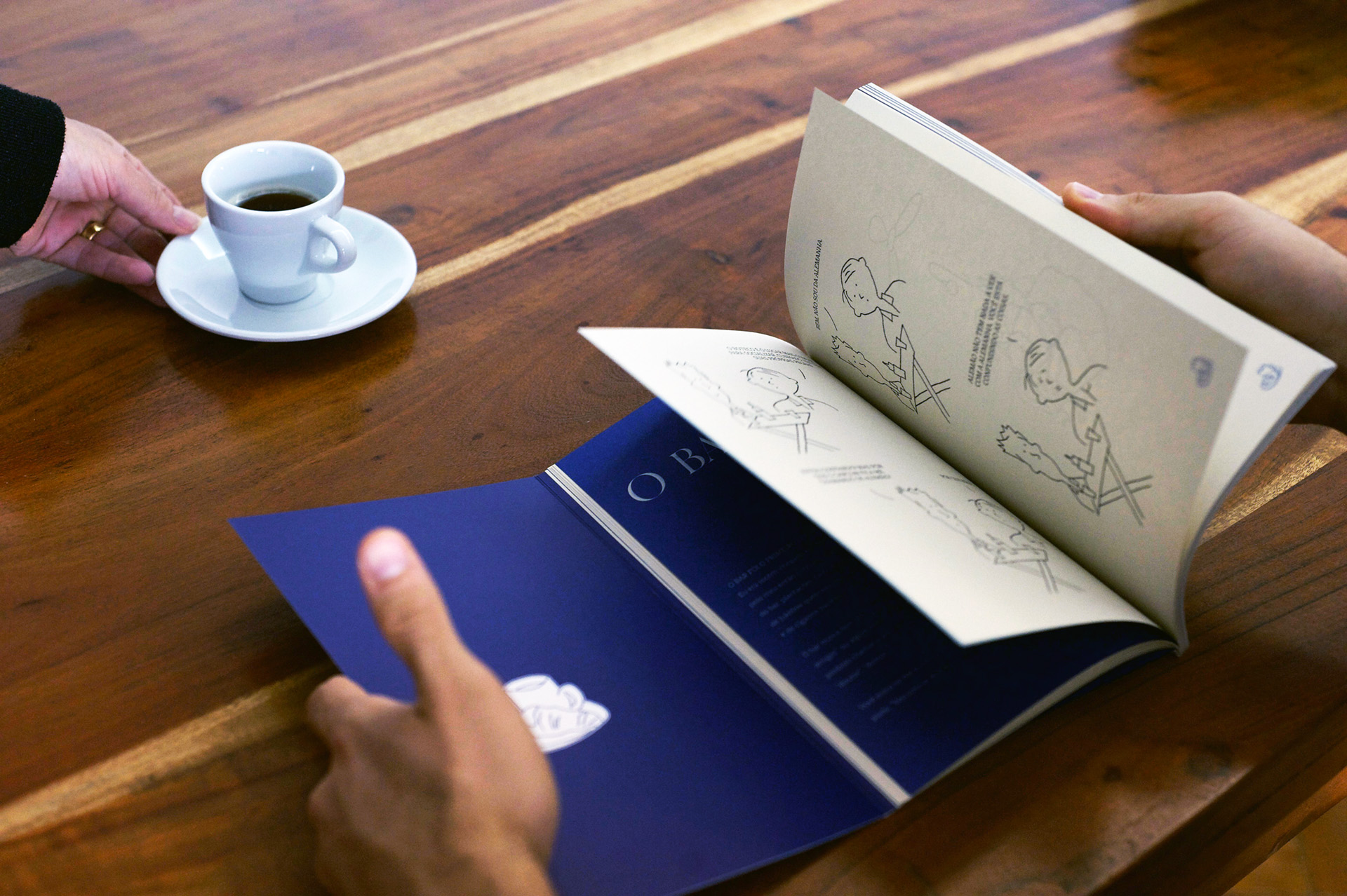 Páginas interiores com cartoons a traço, ao lado de uma chávena de café