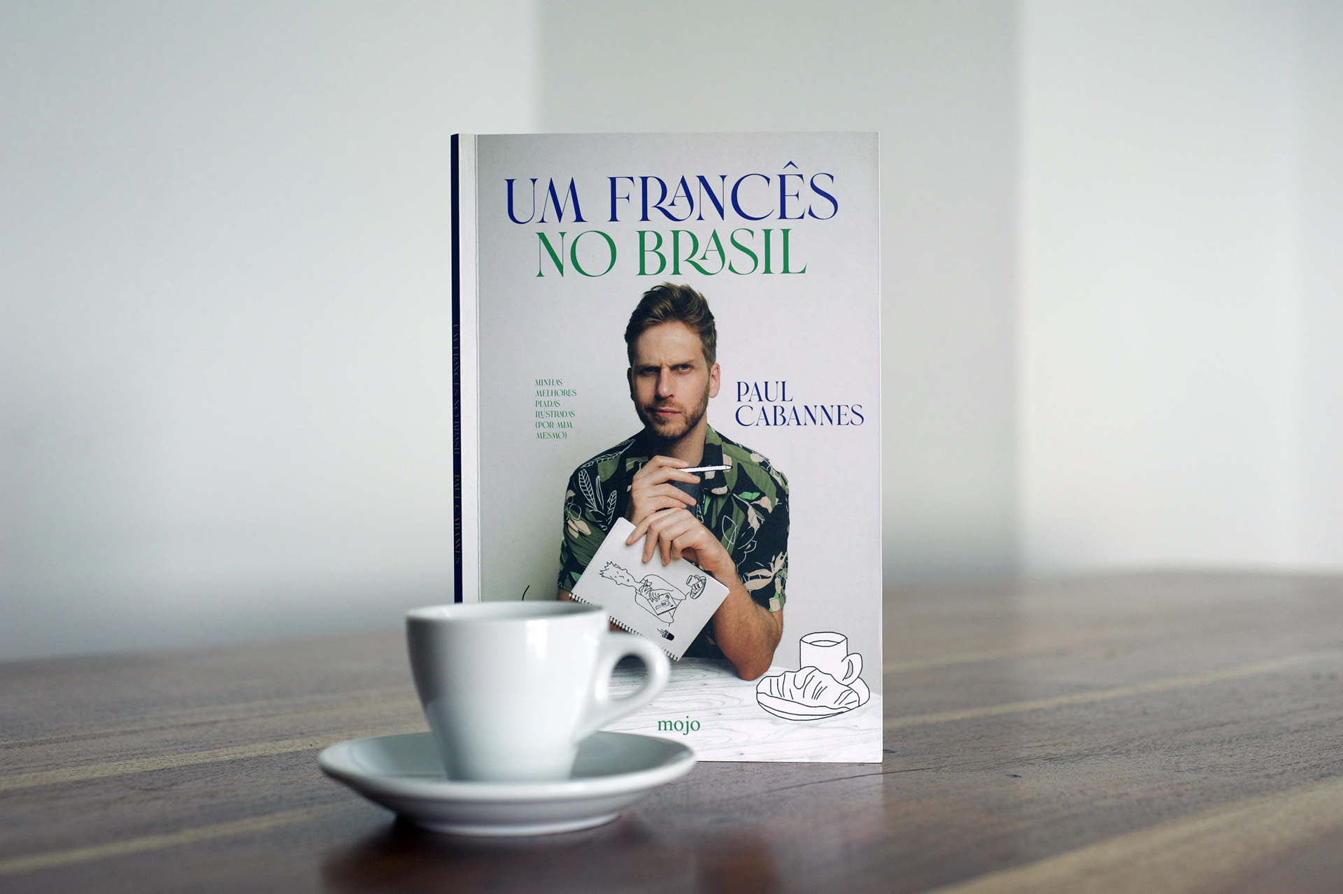 Capa do livro Um francês no Brasil, de Paul Cabannes, com o retrato do autor, sobre uma mesa ao lado de uma chávena de café