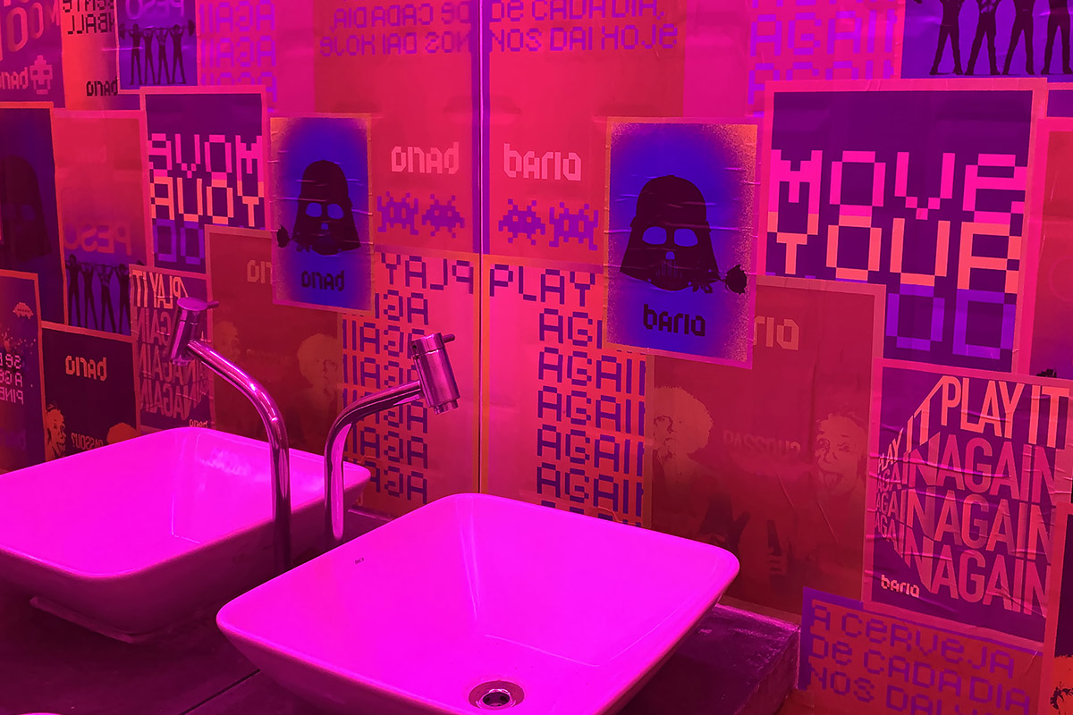 Bário toilets with magenta-lit basins and posters on the walls