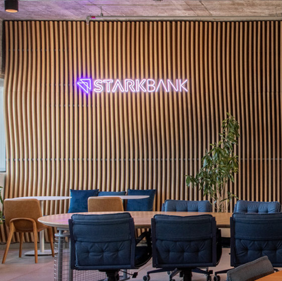 Meeting room with the Stark Bank neon logo on the slatted wall